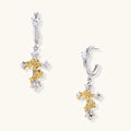 Two-tone huggie hoops with gold rose crosses and star zirconia accents on cream background